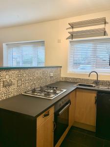 a kitchen with a stove top oven next to two windows at DIDSBURY Fáilte Inn Apts - 3 Mins to The Christie's - Ground Floor - FREE Parking in Manchester