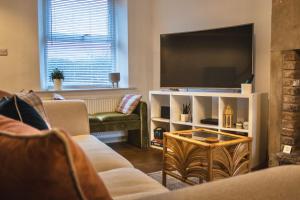 a living room with a flat screen tv and a couch at Spa Garden Cottage - Upper Hopton in Mirfield