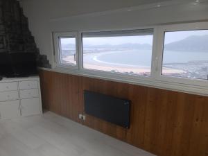 a room with two windows and a tv and a beach at Torre de laredo 9-3 in Laredo