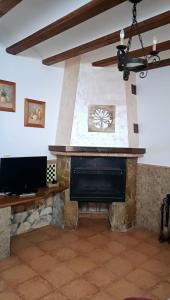 sala de estar con chimenea de piedra y TV en Casas Alcala, en Alcalá del Júcar