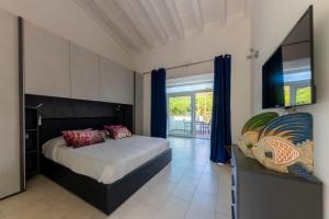 a bedroom with a bed with blue curtains and a television at ***Villa Prestige**** in Capoliveri +35 photos