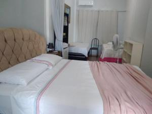 a bedroom with a large white bed and a chair at Studio confortavel - ate 4 pessoas in Araranguá