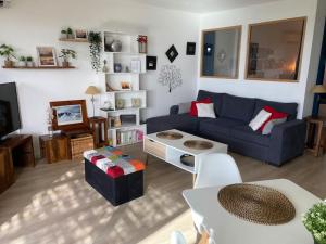 uma sala de estar com um sofá azul e uma mesa em Appartement vue mer mont des oiseaux em Hyères