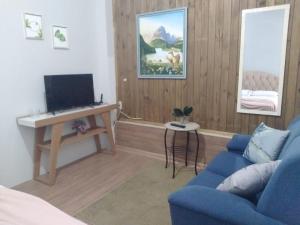 アララングアにあるStudio confortavel - ate 4 pessoasのリビングルーム(青いソファ、テレビ付)
