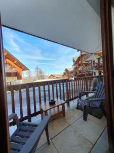 a porch with two chairs and a table on a balcony at Montagne Les Orres in Les Orres