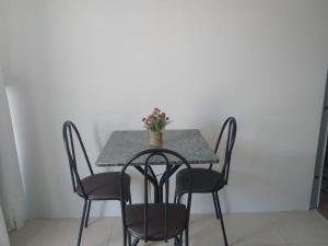 una mesa con sillas y un jarrón de flores. en Studio confortavel - ate 4 pessoas, en Araranguá