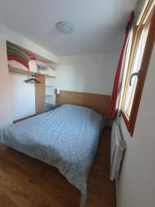 um pequeno quarto com uma cama e uma janela em Montagne Les Orres em Les Orres