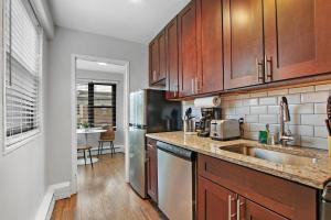 a kitchen with wooden cabinets and a stainless steel refrigerator at Chic & Cozy 1BR Apt in Chicago - Hyde Park 408 in Chicago