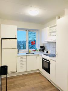 una cocina con armarios blancos y una ventana en Scandinavian Apartment Hotel - Torsted - 2 room apartment en Horsens