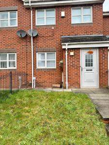 una casa in mattoni con una porta bianca e un cortile di Home Sleeps5-Netflix-parking-near City Centre-Etihad-Coop Live a Manchester