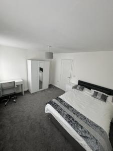 a white bedroom with a bed and a desk at Manchester home near City Centre and City stadium in Manchester