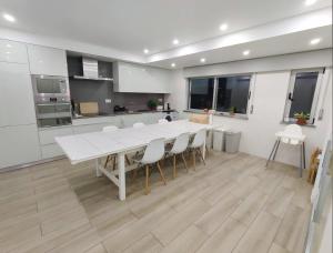 SUPERTUBOS HOUSE Peniche في بينيش: مطبخ مع طاولة بيضاء كبيرة وكراسي