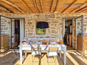 a white table with chairs in a room with a stone wall at Casa nel Bosco, un oasi di pace in Seccheto