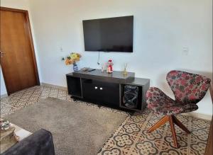 a living room with a television and a chair at Recanto NS Aparecida in Socorro