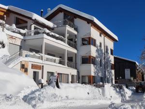 un edificio de apartamentos cubierto de nieve con una pila de nieve en Ferienhof PUA en Sent