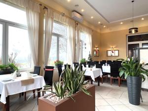 un restaurant avec des tables blanches, des chaises et des plantes dans l'établissement Hotel Kłodzko, à Kłodzko