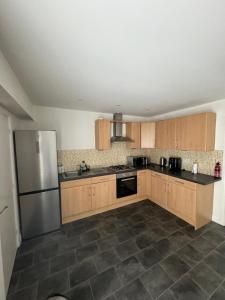a kitchen with wooden cabinets and a stainless steel refrigerator at Manchester home near City Centre and City stadium in Manchester