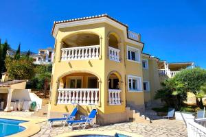 een geel huis met stoelen en een zwembad bij Villa Flor de Neu in Denia