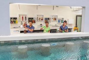 un groupe de personnes assises à un comptoir près d'une piscine dans l'établissement Cosy studio - Trou-aux-Biches, à Trou aux Biches