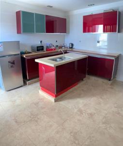Appartement Yoff Virage vue panoramique sur mer في داكار: مطبخ مع دواليب حمراء وثلاجة ستانلس ستيل
