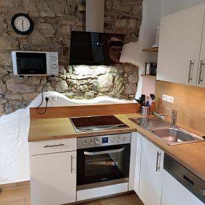 a kitchen with a stove and a sink and a stone wall at Ferienwohnung Lampertstal in Alendorf, Toskana der Eifel in Blankenheim
