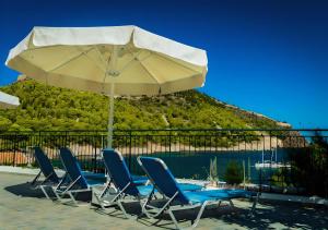 a group of chairs and an umbrella next to a pool at Dionos Villa in Asos