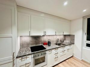 cocina con armarios blancos y encimera en Exclusive apartment for families and business en Uster