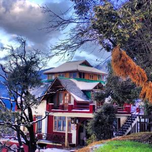 a red house with a mountain in the background at Naddi Castle in McLeod Ganj