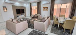 a living room with couches and a table and a television at Jabal Masfut Villa استراحة جبل مصفوت in Sharīyah