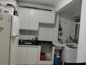 a kitchen with white cabinets and a sink and a refrigerator at Aphostel compartilhado gatinhos perças in Santos