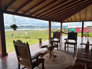 une terrasse couverte avec une table et des chaises et une vue sur un champ dans l'établissement Casa Campestre Lago Calima, à Calima
