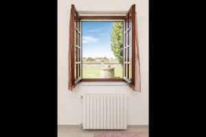 une fenêtre ouverte avec un radiateur et une vue sur un champ dans l'établissement Oasi di Pace Sarzana, à Luni