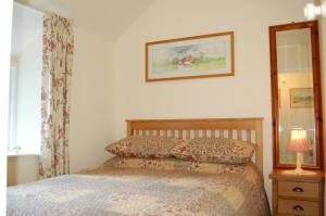 a bedroom with a bed and a lamp and a mirror at Bronhaul Cottage in Pennal in Pennal