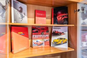 półka z książkami i grami na niej w obiekcie Ferrari Museum & Train Station - Il Cavallino Loft w mieście Modena