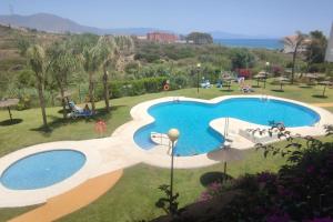 uma grande piscina com pessoas sentadas à sua volta em Seaview Penthouse Magnificó Ático Duplex con vistas al mar em Manilva