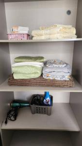 Armario blanco con toallas, cesta y estante en Confortável Studio no Park Sul próximo ao aeroporto, en Brasilia