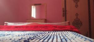 a bedroom with a bed with a red blanket and a mirror at Ketama hachiche in Tlata Ketama