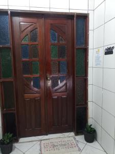 a wooden door in a bathroom with two plants at Casa Eco Via Norte - MCZ in Maceió