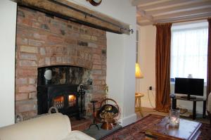 sala de estar con chimenea de ladrillo y sofá en Bronhaul Cottage in Pennal, en Pennal