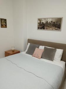 una camera da letto con letto, lenzuola e cuscini bianchi di Residence Il Pavone a Sassari