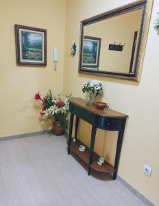 Zimmer mit einem Tisch mit Blumen und einem Spiegel in der Unterkunft Banda del Rio in Bueu