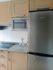 een keuken met een roestvrijstalen koelkast en een magnetron bij Piso de 4 habitaciones in O Grove