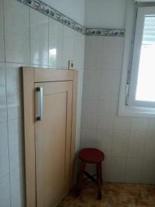 een kleine badkamer met een houten deur en een kruk bij Piso de 4 habitaciones in O Grove