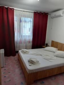 a bedroom with a large bed with red curtains at Marisol 2 in Eforie Nord