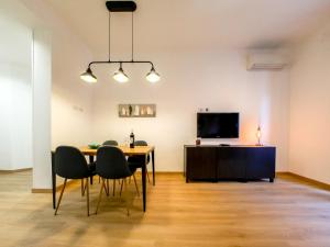 comedor con mesa, sillas y TV en Chic Modern 2-Bedroom near Metro, en Roma