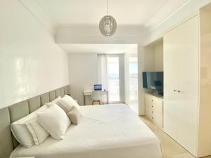 Un dormitorio blanco con una cama y un televisor. en Anfa Finance City CFC! Magnifique Apt Tours Végétales, grande terrasse, piscine, parking, en Casablanca 10 fotos más