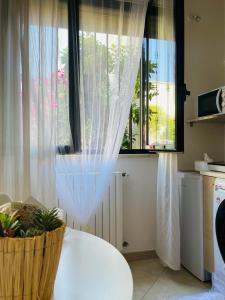eine Küche mit einem Fenster mit einem weißen Vorhang in der Unterkunft Macadà in Bari