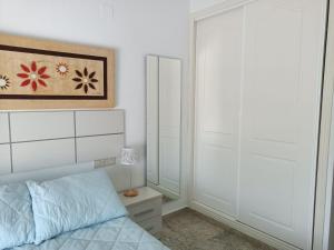 Apartamento en Motril-costa de Granada في موتريل: غرفة نوم بسرير وخزانة ومرآة