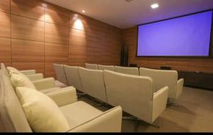 una sala de conferencias con sillas blancas y una pantalla grande en Confortável Studio no Park Sul próximo ao aeroporto, en Brasilia