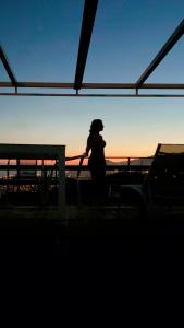 une femme debout à côté d'une clôture au coucher du soleil dans l'établissement Studio Geek Villa - Open Space - all year round Pool, Dining Pergola, Barbecue - Funchal Holiday Home by Salviati Stays, à Funchal